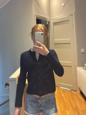 Mörkblå kofta från Zara - Mörkblå kofta från Zara med rund halsringning och knäppning framtill. Långärmad och i mjukt stickat material, perfekt att slänga över en t-shirt eller linne. Enkel och stilren design som funkar till det mesta.