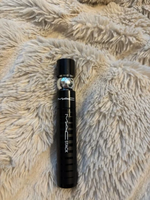 MAC Stack Mascara svart - MAC Stack Mascara i svart med elegant, matt svart hylsa och silverdetalj. Cylindrisk form med tydlig logga och modern design. Perfekt för att skapa volym och längd till fransarna. Snygg och stilren tub som känns lyxig i handen.