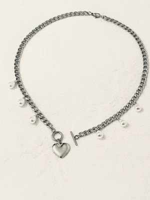 Silverfärgat halsband med pärlor och hjärta - Stilrent halsband i silverfärgad metall med små vita pärlor längs kedjan och ett hjärtformat hänge. Halsbandet har en snygg toggle-låsning framtill som ger en trendig touch. Perfekt accessoar för att lyfta din outfit.