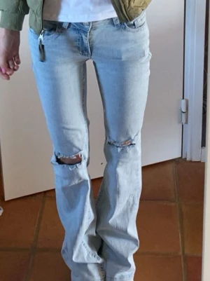 Ljusblå bootcut jeans med hål - Säljer ett par ljusblå bootcut jeans ifrån nelly med hål, i storlek 34. de är lite slitna längst ner, men inget som är sönder💕