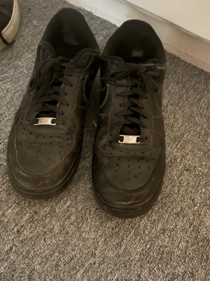 Svarta Nike Air Force 1 sneakers - Black AF1 , acceptabelt skick. Lite slitna men ser fortfarande bra ut och funkar.