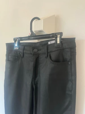  Skinnbyxor från Vero Moda - Snygga utsvängda svarta skinnbyxor från Vero Moda med klassisk femficksmodell och vanlig midja. Materialet är stretchigt för extra komfort.