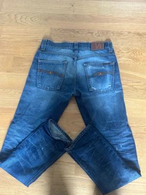 Blå slitna jeans från Nudie Jeans - Tjena. Säljer dessa otroligt feta och unika Nudie jeans i storlek 31/32! Jeansen är i 10/10 skicka förutom att den vänstra fickan har ett hål (se bild). Pris kan självklart diskuteras. Hör av dig om du har några funderingar🤩