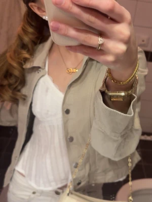 Beige jeansjacka med silvriga knappar - Snygg beige jeansjacka med klassisk krage och silvriga knappar framtill. Jackan har en figurnära passform och är tillverkad i jeansmaterial. Perfekt att slänga över en topp för en cool och avslappnad look.