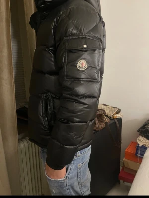 Svart Moncler pufferjacka med huva - Tja! Säljer en svart pufferjacka från Moncler i storlek M~S/ modellen är 1.80 En väldigt liten defekt framtill högra bröstet samt vid bakdelen av jackan( som visas på bilderna). Annars i väldigt fint skick. Säljer för ett relevant pris. Självklart äkta. DMa