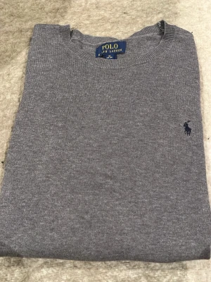 Grå stickad tröja från Polo Ralph Lauren - Snygg grå stickad tröja från Polo Ralph Lauren. Storlek är S/XL (kids). 
