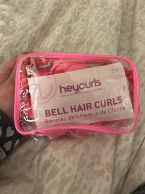 Heycurls Bell Hair Curls rosa hårspolar - Säljer ett set med 18 (fattas 2)  rosa Bell Hair Curls från Heycurls. Kommer i en genomskinlig necessär med rosa kant. Perfekta för att skapa lockar utan värme. Smidiga att använda och lätta att ta med sig. Instruktioner medföljer i förpackningen.
