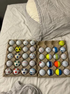 Samling golfbollar med olika mönster - En samling golfbollar från Callaway, TaylorMade och Vice med olika färger och mönster, bland annat fotbollsmönster, stjärnor, flaggor och randiga designer. Perfekt för dig som vill sticka ut på golfbanan eller samla unika golfbollar. Skriv bud