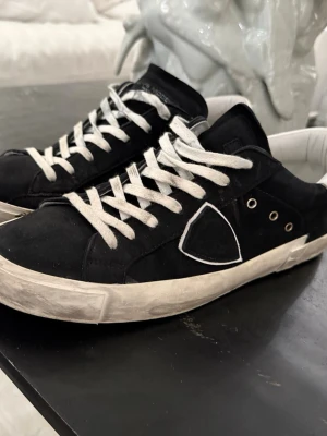 Philippe Model svarta sneakers - Svarta Philippe Model sneakers med vit sula och vita detaljer. Skorna är knappt använda endast ca 10 gånger och har även kvar lådan. Storlek 43 kan tänka mig att sänka priset vid en snabb affär