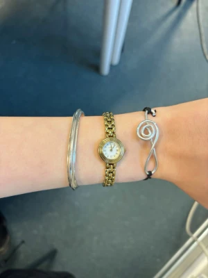 Silvrigt armband med spiraldesign - Unikt armband med en spiralformad dekoration i silverfärgad metall och svart justerbart band. Den minimalistiska designen ger en cool och modern känsla, perfekt för dig som gillar stilrena accessoarer med en twist.