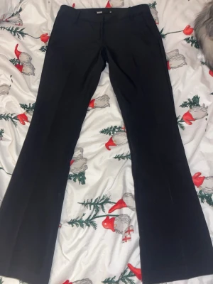 Svarta kostymbyxor bootcut - Snygga svarta kostymbyxor med bootcut passform och klassisk midja. Byxorna har pressveck och hällor för skärp. Perfekta för en stilren look och passar till skjorta eller topp.