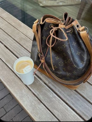 Louis Vuitton Monogram Noé handväska (likhet)  - en brun handväska som liknar en lv väska, köpt secondhand och därmed antar jag att den ej är äkta, första bilden är inte min alla andra är. skriv för fler bilder om det behövs 