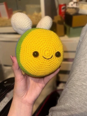 Virkat bi - Säljer ett handgjort virkat bi med regnbågsfärgade ränder på baksidan och gul framsida. Virkat i bomullsgarn.