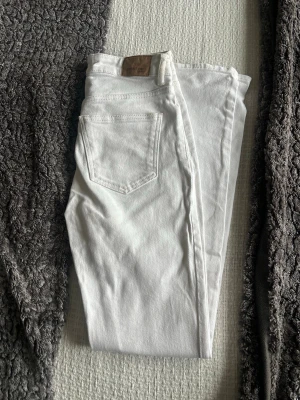 Vita raka jeans från ginatricot  - Snygga vita jeans från ginatricot med klassisk femficksdesign och raka ben. Jeansen har en läderpatch med logga bak i midjan och är tillverkade i ett mjukt denimtyg. Perfekta för en fräsch och stilren look.