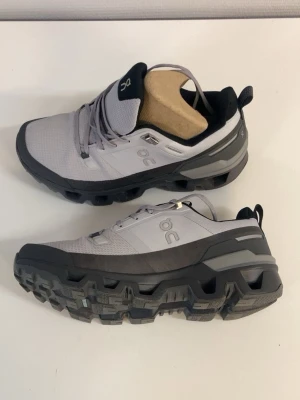Grå On Cloud sneakers med grov sula - Vandringsskor i storlek 42 säljes. Skorna är endast använda 1–2 gånger och är i mycket bra skick. Passar alla väder. Nypris 1600 kr, säljes för 1350kr.