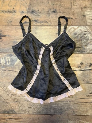 Vintage söt Odd Molly linne - Snyggt linne i satinliknande material med justerbara axelband. Dekorerat med ljusrosa spets längs nederkant och framtill. Perfekt för dig som gillar en romantisk och mjuk stil på dina underkläder.