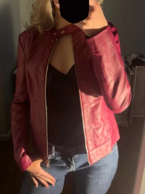 Vinröd/mörkrosa bikerjacka - Säljer denna assnygga skinnjackan från  jacqoueline de young, färgen är mer mot de vinröda/mörkrosa hållet och det är en perfekt jacka inför våren. Storleken är 34 men skulle säga att den är lite mer mot de mindre hållet då det är den storleken jag brukar ha i jackor vanligtvis men den är lite för tajt över axlarna för mig. Därmed anledningen till varför jag säljer💕Inte äkta skinn! Endast andvändt något fåtal gånger och är i mycket bra skick!