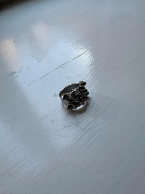 Silvrig ring med nitar - Cool ring i silverfärgad metall med flera små nitar runt ovansidan. Ringen har en chunky och edgy design som sticker ut och passar perfekt för dig som gillar statement-smycken. Ingen synlig märkning på insidan.