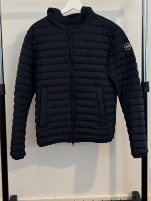 Blå dunjacka från Colmar - Säljer en blå dunjacka från Colmar som är i princip ny. Jackan har quiltad design med horisontella sömmar och Colmar-logga på ärmen. Använt några gånger och den är utan defekter eller synlig användning så den är i mycket bra skick.