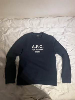 Marinblå APC hoodie storlek M - Säljer en mörkblå hoodie från APC i storlek M. Sjukt bra kvalitet och kraftigt tyg som håller formen perfekt. Clean modell som passar till typ allt.Använd men i fint skick. Finns inga hål eller vanliga fläckar, men om man lyser med skarpt ljus på den kan man se några små parfymfläckar, inget man märker alls när man bara har på sig den.