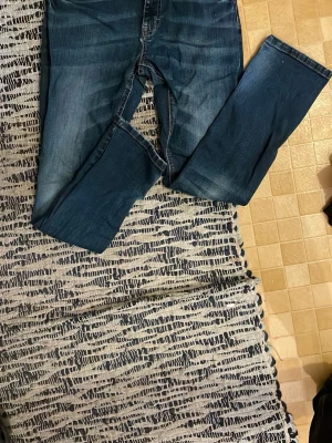 Blå raka jeans från H&M - Mörkblå jeans med raka ben från H&M. Klassisk femficksmodell med dragkedjegylf och bälteshällor. Jeansen har lätt slitna detaljer och är gjorda i denim av bomull. Perfekta för en avslappnad och stilren look.
