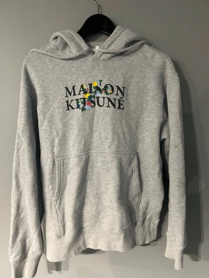 Maison kitsune Hoodie  - Grå hoodie från Maison Kitsuné säljes. Använd väldigt lite och är i fint skick utan slitage. Storlek S vilket är svårare att få tag på.  Skickar snabbt och kan självklart skicka fler bilder eller svara på frågor vid intresse.