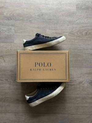 👟 Polo Ralph Lauren sneakers – Klassisk stil med premium känsla  - Snygga mörkblå sneakers från Polo Ralph Lauren. Stilren och tidlös modell som passar perfekt till både jeans, chinos och shorts. Bekväma vardagsskor med klassisk design som aldrig går ur mode.  ✔️ Polo Ralph Lauren ✔️ Mörkblå färg med vita detaljer ✔️ Låg modell ✔️ Bekväma och mångsidiga ✔️ Perfekta för vardag och fritid ✔️ Originalkartong medföljer  Märke: Polo Ralph Lauren Färg: Mörkblå / Navy Typ: Sneakers Skick: Begagnat skick (se bilder för detaljer)