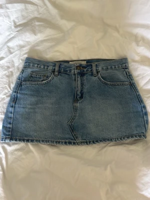Blå lågmidjad jeanskjol från Stradivarius - Säljer en klassisk blå jeanskjol från Stradivarius. Kjolen är kort, lågmidjad, har fem fickor, bälteshällor och stängs med knapp och dragkedja framtill. Perfekt basic-plagg att matcha med allt i garderoben.🤗🌸