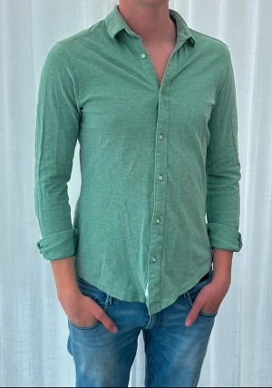Grön långärmad skjorta i bomull från only & sons  - Snygg grön skjorta med lång ärm och klassisk krage. Skjortan har knappar hela vägen framtill och är gjord i mjuk bomull. Perfekt till jeans för en avslappnad men stilren look.