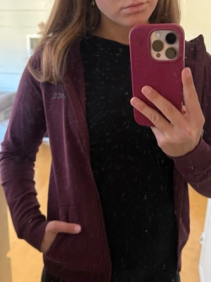 Vinröd ziptröja från Peak Performance - Snygg vinröd ziptröja från Peak Performance med diskret logga på bröstet. Tröjan har hel dragkedja, hög krage och fickor på sidorna. Perfekt till träning eller som ett extra lager. Materialet känns mjukt och stretchigt.