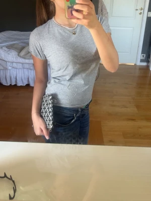 Grå basic t-shirt i bomull - En enkel och stilren grå t-shirt med rund hals och korta ärmar. Tillverkad i mjuk bomull som passar perfekt till jeans eller shorts. Snygg och tidlös modell som är lätt att matcha med olika outfits.