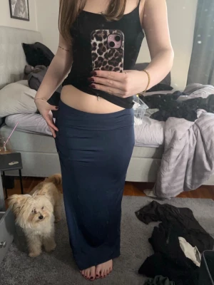 Mörkblå lång kjol med slits - Säljer en mörkblå, figurnära långkjol med hög midja och en snygg slits på sidan. Kjolen har rynkade detaljer baktill och är gjord i ett mjukt, stretchigt material som sitter skönt på kroppen❤️