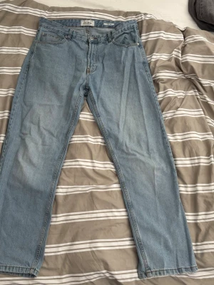 Ljusblå wide leg jeans Pull&Bear - Säljer ett par ljusblå jeans från Pull&Bear med wide leg-modell. Klassisk femficksdesign och raka ben. Jeansen är tillverkade i bomull och har en avslappnad passform som är perfekt för en trendig och chill stil.