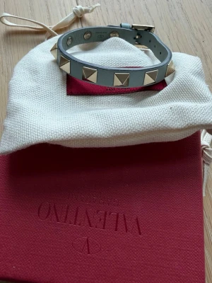 Valentino nitarmband - Armbandet är ljusblått med nitar. Med kommer låda med dust bag, äkthetsbevis, extra nitar samt kvitto. 