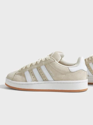 Beige Adidas Campus sneakers - Snygga beige Adidas Campus sneakers i mocka med klassiska vita ränder på sidorna och vit sula med gummidetalj. Skorna har breda vita skosnören och låg profil. Perfekta för en avslappnad streetwear-look.