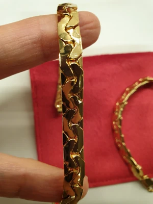 Guldigt armband från Armani - Säljer ett chunky armband från Armani i glänsande guldfärgad metall. Armbandet har breda, vågiga länkar och ett robust spänne med märkets logga ingraverad. Perfekt för dig som gillar statement-accessoarer.