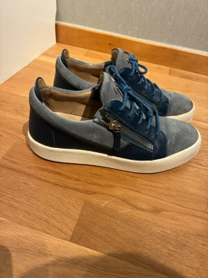 Giuseppe zanotti Blå sneakers med dragkedja - Snygga sneakers från Giuseppe Zanotti i blått och mocka och läder. Skorna har vita sulor, blå skosnören och coola dragkedjor på sidorna. Perfekt för dig som vill ha en unik och trendig look.