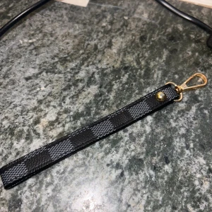 Rutigt nyckelband i svart och grått - Snyggt nyckelband med rutigt mönster i svart och mörkgrått. 