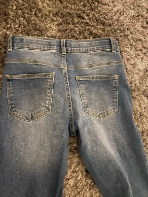 vero moda Blå bootcut jeans  - Ett par blå bootcut jeans med lätt slitna detaljer och klassiska fem fickor.  Materialet är denim i bomull. 