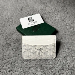 Vit kortfodral - Snyggt vitt kortfodral med stilrent mönstermönstret och logotyp fram. Perfekt för dig som vill ha något stilrent och lyxigt i fickan. Lätt användt i bra skick!