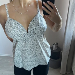 Blommig sommartopp - Söt topp med småblommigt mönster i vitt och ljusblått. Sytt den själv av ett bomullstyg från selfmade. Finns ett litet bränn märke som knappt syns (bild 5). Sydde toppen i storlek S, hör av er vid frågor om mått eller annat!💗