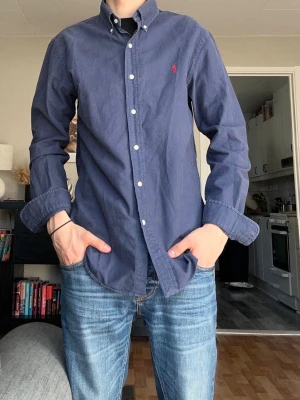 Polo Ralph Lauren Slim Fit Skjorta - | Polo Ralph Lauren | Skjorta | Slim Fit | Blå | Röd Logga | Medium | 399kr | Mycket Bra Skick |  Bredd: 45cm Längd: 70cm  Pris ej hugget i sten🪨  Skickas inom 24h📦  Kontakta vid minsta fråga eller fundering🤩