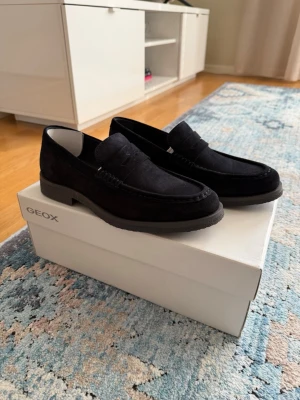 Geox moccasins (marinblå) - Säljer ett par stilrena loafers från Geox i mjuk mocka. Klassisk penny loafer-design med diskret söm längs kanten och låg klack. Perfekta för sommaren och hösten! 
