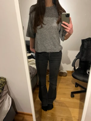 Grå trekvartsärmad stickad tröja - Säljer en grå oversized stickad tröja som är trekvartsärmad och rund halsringning. Tröjan har en avslappnad passform och är gjord i mjukt material.