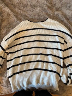 Randig stickad tröja från ONLY - Säljer en vit stickad tröja från ONLY med svarta horisontella ränder. Tröjan har en avslappnad passform, ribbad struktur och långa ärmar. Perfekt för dig som gillar en enkel men snygg stil.