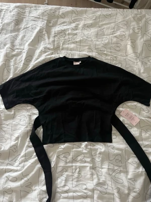 Svart T-shirt  - Säljer en söt svart T-shirt men knyt i ryggen! Aldrig använt den så prislappen är kvar💞