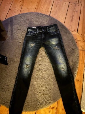 mörkblå replay anbass med slitningar - Säljer ett par svarta Replay Anbass jeans med slitningar. Storlek W30/L32 