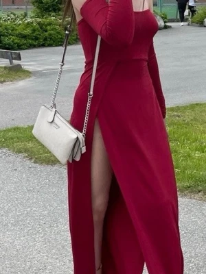 Röd offshoulder långklänning - Snygg röd långklänning med offshoulder-design och långa ärmar. Klänningen har en enkel, elegant siluett och är perfekt för dig som vill sticka ut. Tillverkad i ett mjukt och följsamt material som ger en bekväm känsla.