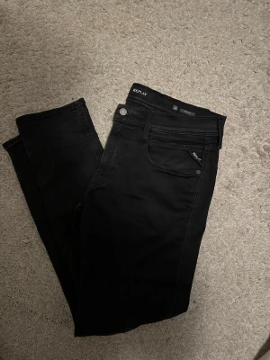 Svarta slim jeans från Replay - Snygga svarta skinny jeans från Replay med klassisk femficksmodell och diskret logga på bakfickan. Jeansen har normal midja, smal passform och är tillverkade i stretchigt material för extra komfort. Perfekta till en trendig streetwear-look.
