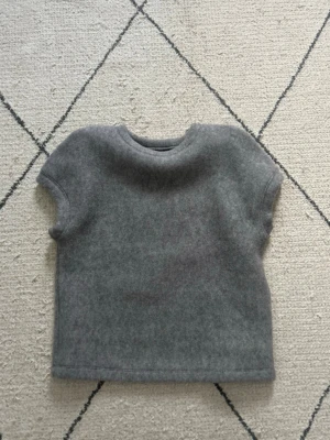 Grå ulltopp med korta ärmar - Minimalistisk grå topp i mjuk ull med rund hals och korta ärmar. Helt ny tröja!!